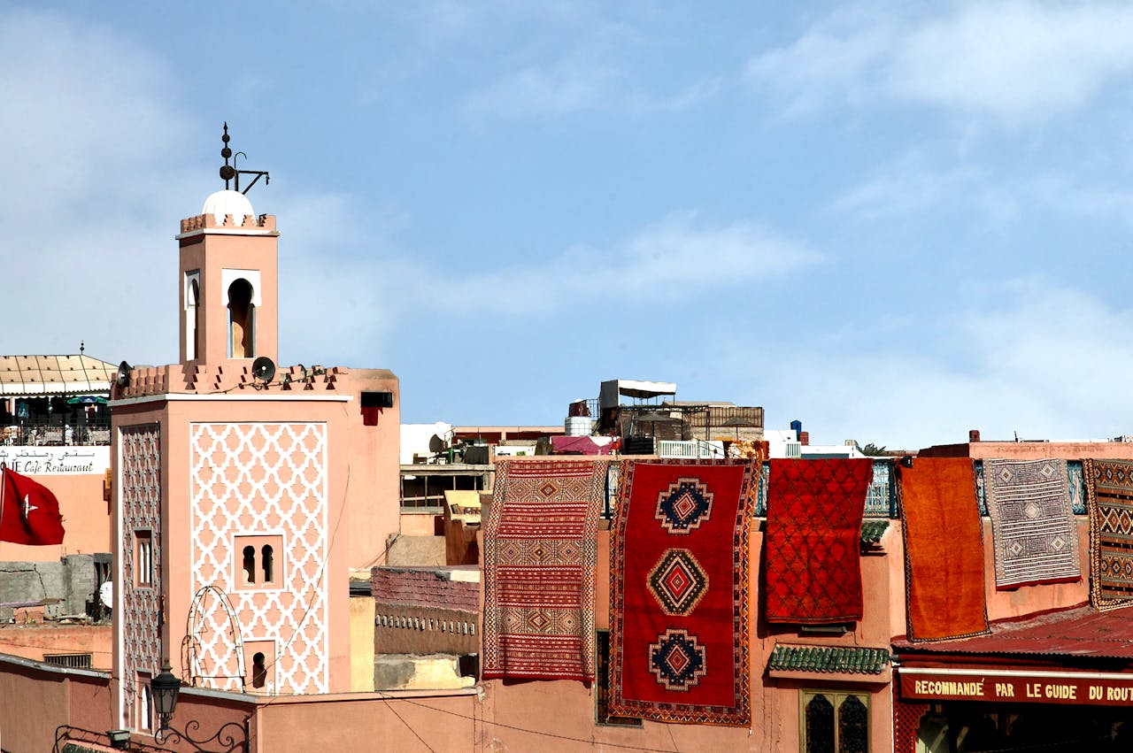 Colorful Moroccan rugs on a rooftop with traditional architecture in Marrakech, Morocco.